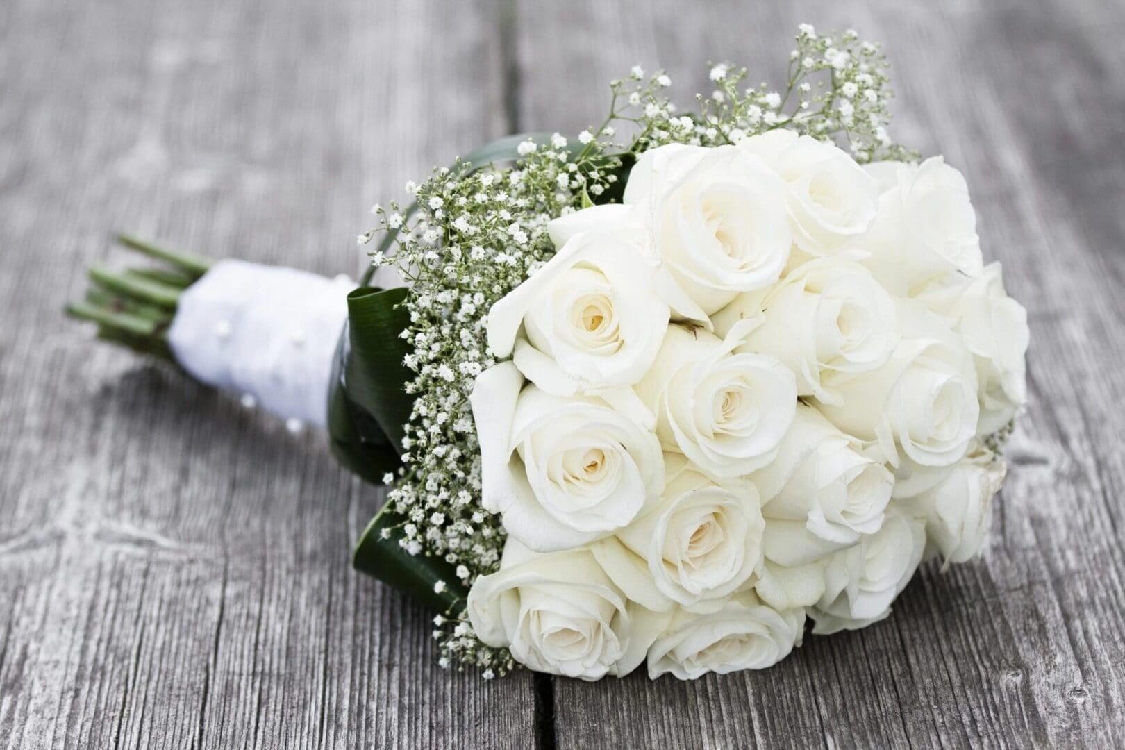 A bouquet of white roses on top of a wooden table.