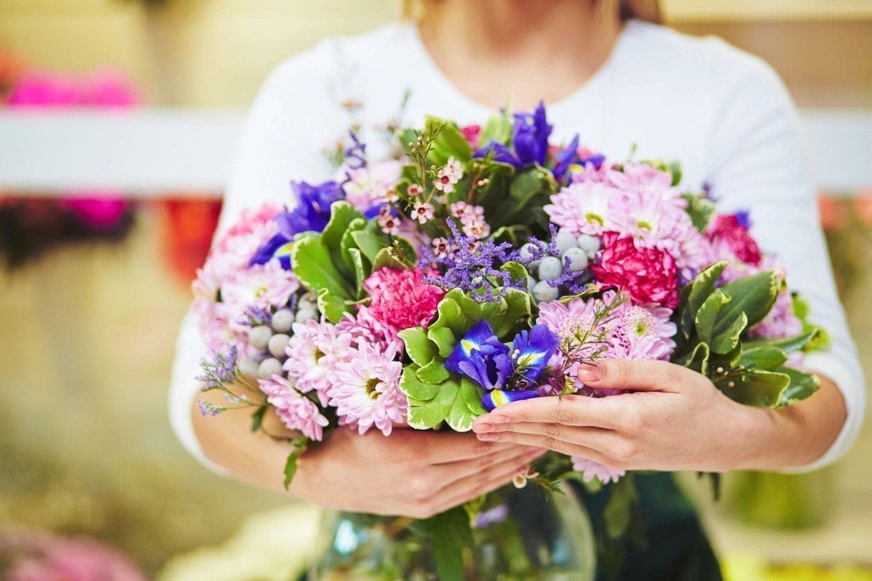 A woman holding a bouquet of flowers in her hands.