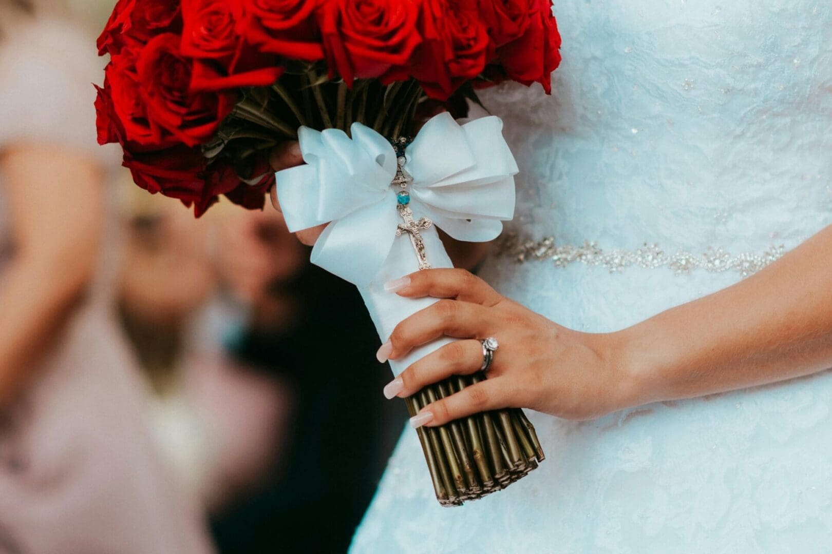 A bride holding her bouquet of red roses.