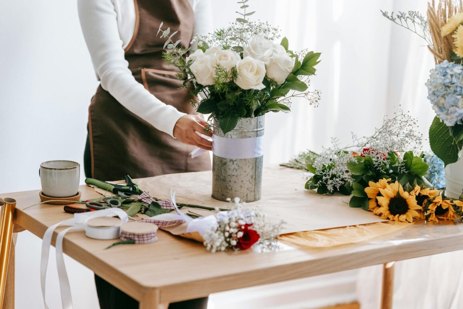 A woman standing at the table with flowers in it.