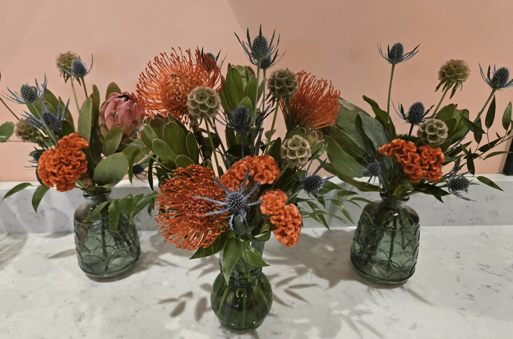 A table with four vases of flowers on it.